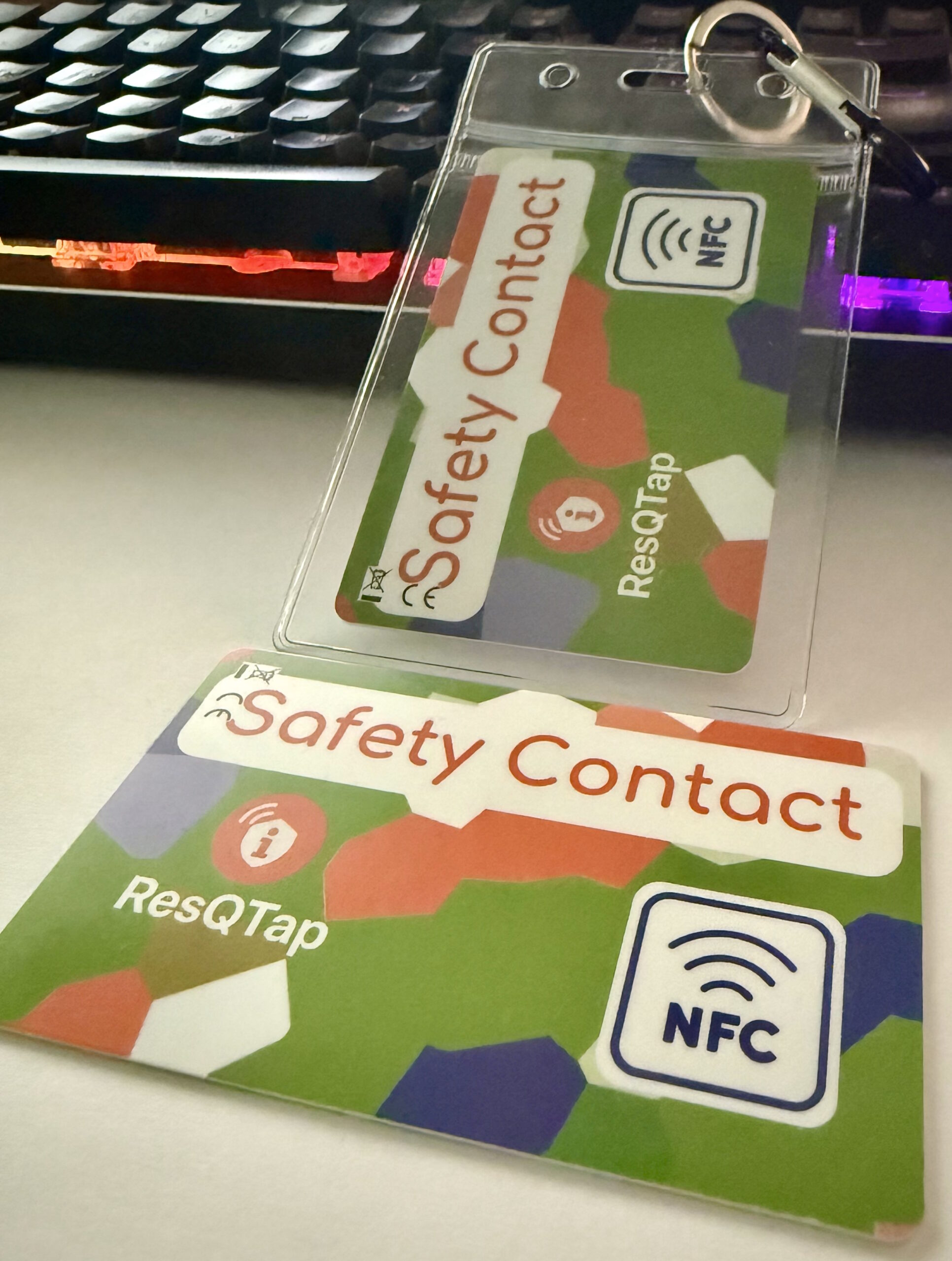 zwei Safety Contact Card, die eine mit Plastikhülle. Auf einem Schreibtisch.