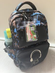 Schwarzer Rucksack, Schulrucksack, mit einer Safety Contact Card in einem Etui und Karabinerhaken
